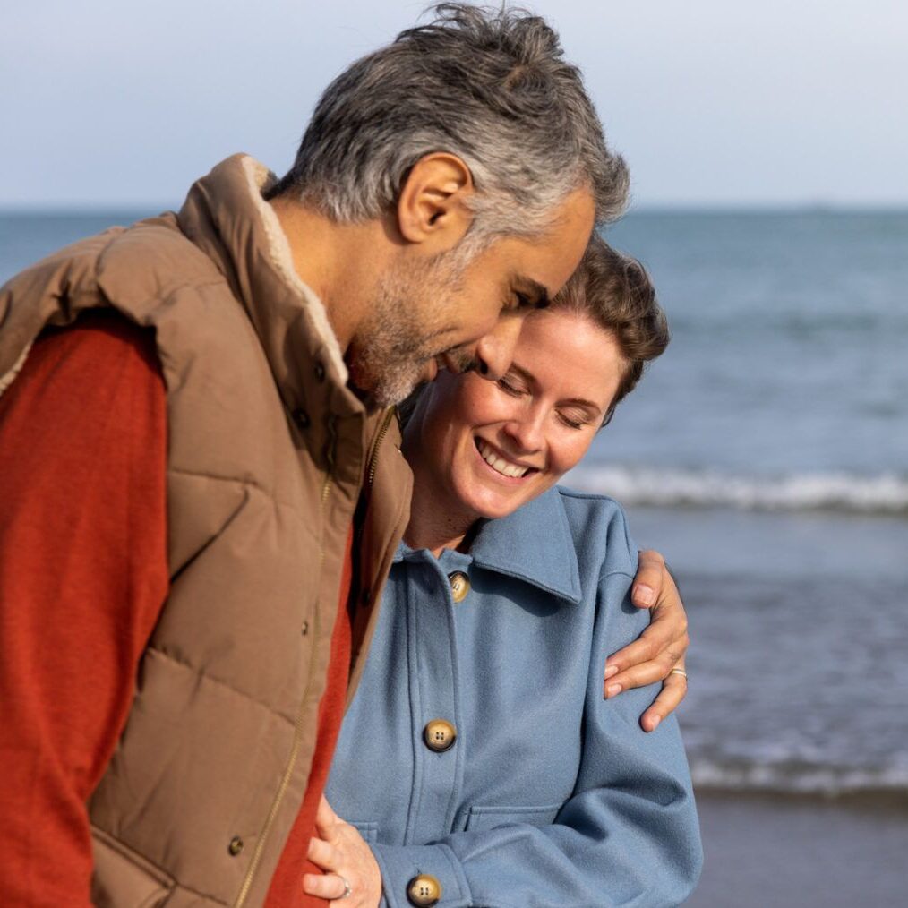 Couple taking a walk on a beach embracing the autumn weather couples therapy reno, nv couple walking on beach, happy